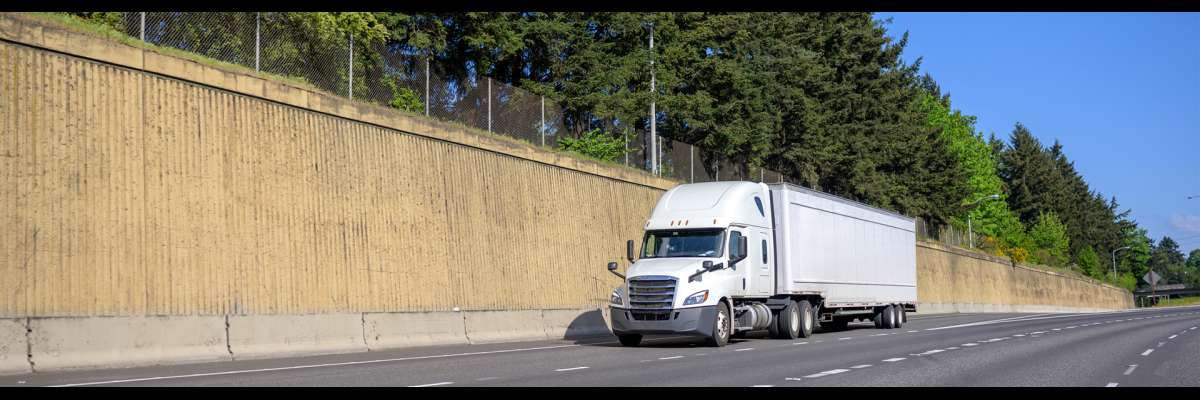 Semi on a freeway next to a sound barrier wall